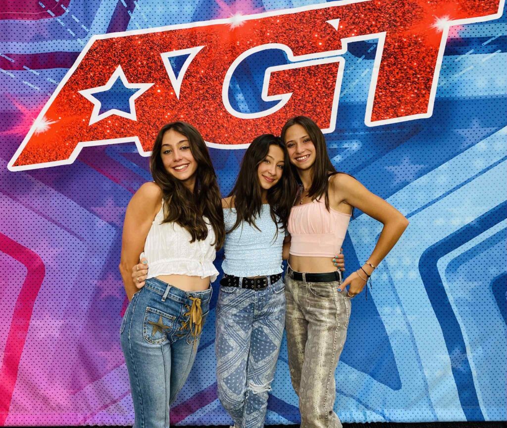 Three girls in front of AGT backdrop  